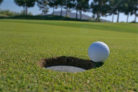 simsearch:400-05370464,k - Low angle view of golf ball next to hole with trees in background Stock Photo - Budget Royalty-Free & Subscription, Code: 400-04444515