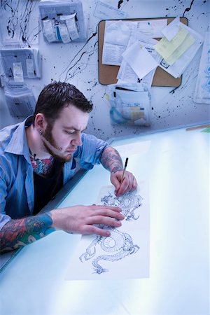Caucasian male tattoo artist drawing tattoo on light table. Fotografie stock - Microstock e Abbonamento, Codice: 400-04445176