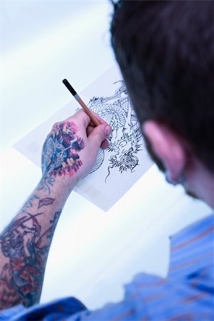 Caucasian male tattoo artist drawing tattoo on light table. Fotografie stock - Microstock e Abbonamento, Codice: 400-04445177