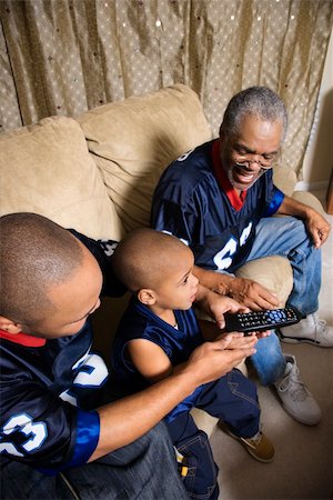 family in sports jerseys - Three male generations of an African-American family watching football game on tv with boy holding remote. Stock Photo - Budget Royalty-Free & Subscription, Code: 400-04445322