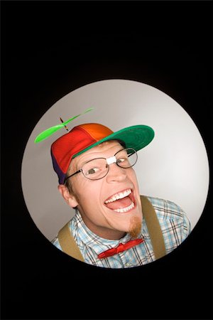 Close up circle vignette of Caucasian young man dressed like nerd wearing propeller cap with mischievous look. Photographie de stock - Aubaine LD & Abonnement, Code: 400-04445591