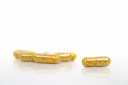 simsearch:400-04347597,k - medical issue - a open pill in front of some other yellow pills on white background Fotografie stock - Microstock e Abbonamento, Codice: 400-04448126