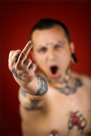 simsearch:400-04186416,k - Caucasian mid-adult man with tattoos and piercings holding up middle finger. Stockbilder - Microstock & Abonnement, Bildnummer: 400-04448238