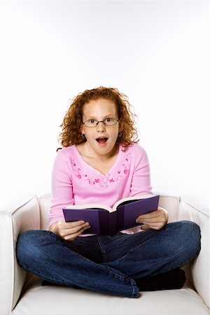 simsearch:400-03923096,k - Caucasian female child sitting reading book looking surprised. Stock Photo - Budget Royalty-Free & Subscription, Code: 400-04448261