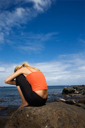 Caucasian young adult woman sitting hugging self on rocky shore. Stock Photo - Budget Royalty-Free & Subscription, Code: 400-04448275