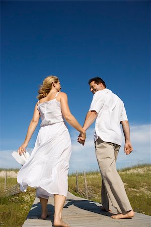 simsearch:400-03943979,k - Caucasian mid-adult couple holding hands walking down beach access path. Foto de stock - Super Valor sin royalties y Suscripción, Código: 400-04448401
