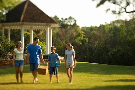 simsearch:400-04953081,k - Caucasian family of four carrying picnic basket walking through park. Foto de stock - Royalty-Free Super Valor e Assinatura, Número: 400-04448909