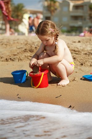 family relaxing with kids in the sun - Cute kid playing with sand on a beach Photographie de stock - Aubaine LD & Abonnement, Code: 400-04449691