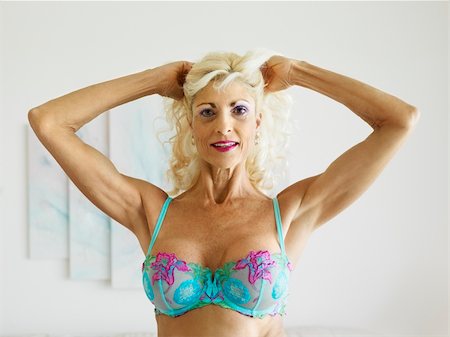 Tan Caucasion blonde middle-aged woman posing in bra with arms over head. Foto de stock - Super Valor sin royalties y Suscripción, Código: 400-04449766