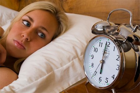 simsearch:700-03554506,k - A beautiful young woman laying in bed watching her alarm clock Stockbilder - Microstock & Abonnement, Bildnummer: 400-04440737