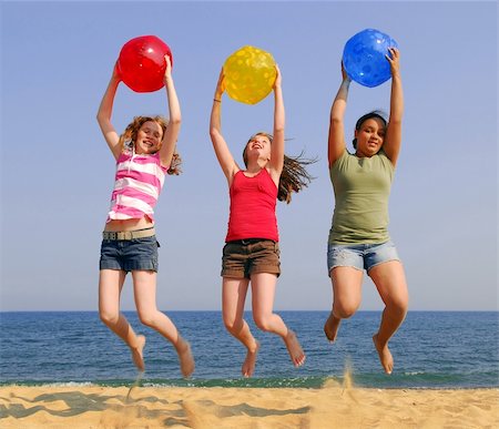 Three girls on a sandy beach jumping with colorful balls Stock Photo - Budget Royalty-Free & Subscription, Code: 400-04443978
