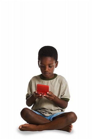 A young, African American boy playing an electronic game. Isolated on white. Foto de stock - Royalty-Free Super Valor e Assinatura, Número: 400-04443989