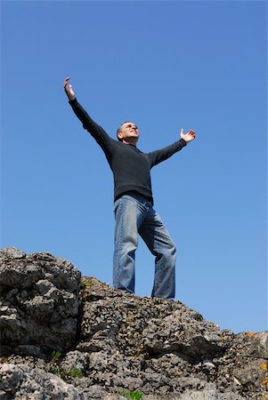 simsearch:400-05147336,k - A man standing on a cliff with his arms raised to the blue sky Foto de stock - Super Valor sin royalties y Suscripción, Código: 400-04454686