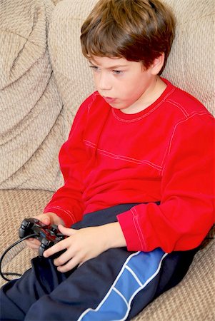 simsearch:400-05059261,k - Young boy playing a video game sitting on a couch Stock Photo - Budget Royalty-Free & Subscription, Code: 400-04455095
