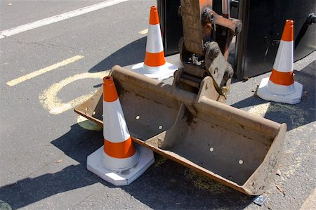 simsearch:400-05111345,k - Small excavator bucket on pavement with some warning signs around Fotografie stock - Microstock e Abbonamento, Codice: 400-04455598