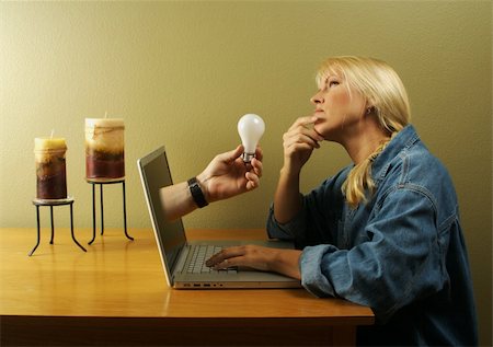 simsearch:400-04455693,k - Attractive businesswoman deep in creative thought while a hand holding a light bulb comes out of her screen. Concept: Internet Inspiration, creative thinking online, ideas, etc. Photographie de stock - Aubaine LD & Abonnement, Code: 400-04455693