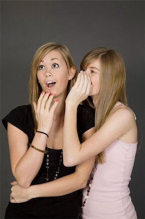 simsearch:400-04960190,k - Teenage girls telling secrets posed in front of a gray background Photographie de stock - Aubaine LD & Abonnement, Code: 400-04456098