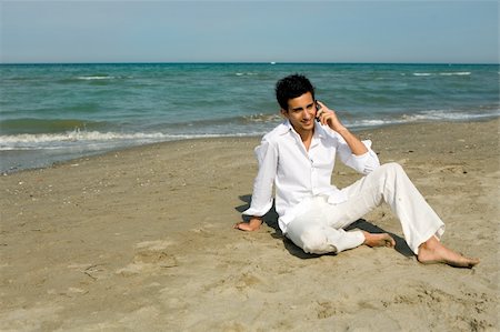 fabthi (artist) - Young attractive man with mobile phone talking sitting in the sand at the beach Foto de stock - Super Valor sin royalties y Suscripción, Código: 400-04457616
