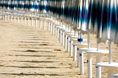 fabthi (artist) - Line of beach-umbrellas closed on a beach in a sunny day Foto de stock - Super Valor sin royalties y Suscripción, Código: 400-04459063