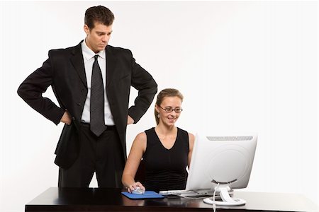 Caucasian mid-adult man with hands on hips looking over shoulder of woman sitting at computer. Stock Photo - Budget Royalty-Free & Subscription, Code: 400-04450049