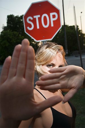 Caucasian mid-adult blonde woman holding hands up to camera in front of stop sign. Foto de stock - Super Valor sin royalties y Suscripción, Código: 400-04451055
