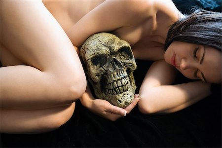 Nude Caucasian young adult woman lying down holding human skull. Stock Photo - Budget Royalty-Free & Subscription, Code: 400-04451145