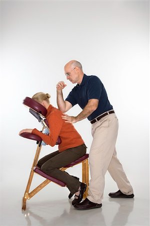 full body massage - Caucasian middle-aged male massage therapist massaging back of Caucasian middle-aged woman sitting in massage chair with his elbow. Stock Photo - Budget Royalty-Free & Subscription, Code: 400-04451354