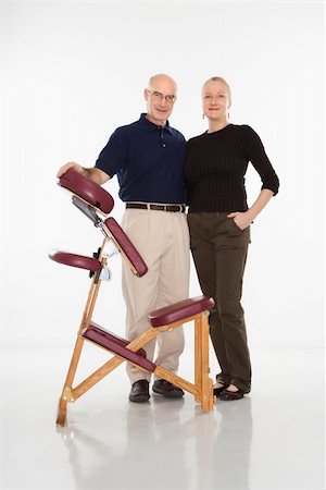 full body massage - Caucasian middle-aged male massage therapist standing with arm around Caucasian middle-aged woman beside massage chair. Foto de stock - Super Valor sin royalties y Suscripción, Código: 400-04451355