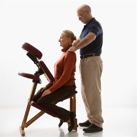 simsearch:400-04956215,k - Caucasian middle-aged male massage therapist massaging shoulders of Caucasian middle-aged woman sitting in massage chair. Photographie de stock - Aubaine LD & Abonnement, Code: 400-04451353