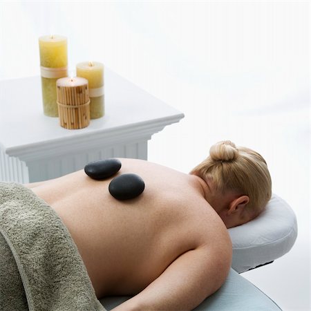 simsearch:400-04956215,k - Caucasian middle-aged woman lying on massage table with hot stones on her back. Photographie de stock - Aubaine LD & Abonnement, Code: 400-04451361