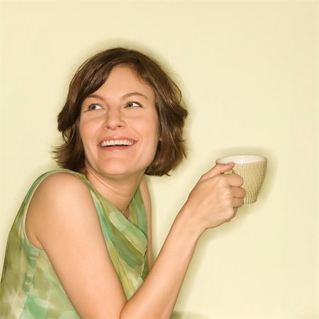 Pretty Caucasian mid-adult woman holding up coffee cup and smiling. Stock Photo - Budget Royalty-Free & Subscription, Code: 400-04451373
