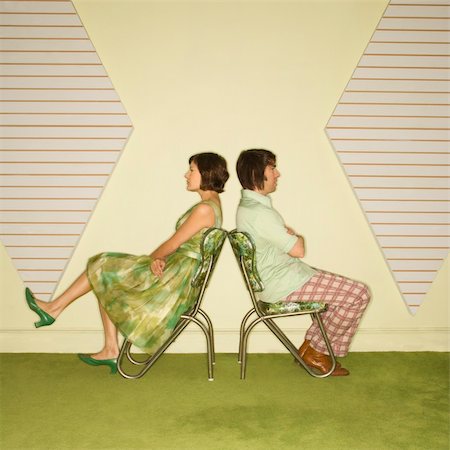 simsearch:400-04451365,k - Caucasian mid-adult couple wearing vintage clothing sitting back to back in green vinyl chairs with arms crossed. Foto de stock - Super Valor sin royalties y Suscripción, Código: 400-04451380