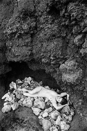 simsearch:400-03940673,k - Young nude Caucasian woman lying down on pile of rocks with hands above head. Stock Photo - Budget Royalty-Free & Subscription, Code: 400-04451729