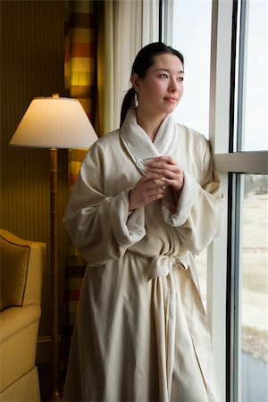 simsearch:400-03926201,k - Taiwanese mid adult woman in bathrobe looking out window holding coffee cup. Fotografie stock - Microstock e Abbonamento, Codice: 400-04451985