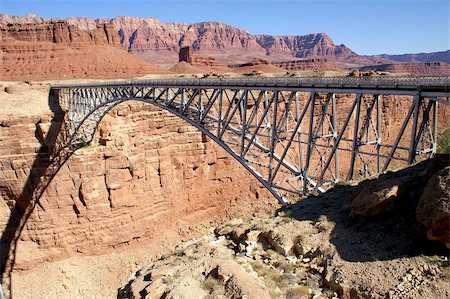 simsearch:400-04486669,k - Built in 1929, this graceful bridge provides one of only two crossings of the Colorado River and Grand Canyon for 600 miles. This original span is now for pedestrians only; a second almost identical bridge was built alongside it in 1995 to carry the traffic. With the Vermillion Cliffs as a backdrop and condors flying below, this location is truly dramatic. Photographie de stock - Aubaine LD & Abonnement, Code: 400-04452322
