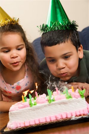 simsearch:400-04452450,k - Hispanic girl and boy wearing party hats blowing out candles on birthday cake. Stock Photo - Budget Royalty-Free & Subscription, Code: 400-04452443
