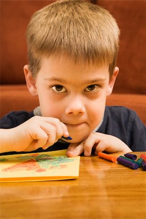 simsearch:400-04957410,k - Caucasian boy drawing with crayons and looking at viewer. Photographie de stock - Aubaine LD & Abonnement, Code: 400-04452456