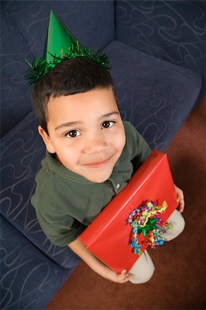 simsearch:400-04452450,k - Hispanic boy wearing party hat holding birthday present looking up at viewer and smiling. Stock Photo - Budget Royalty-Free & Subscription, Code: 400-04452450
