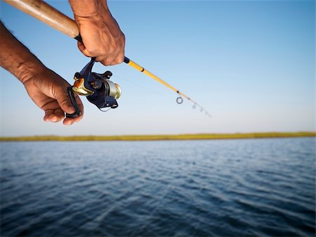 African-American male hand holding fishing rod and reeling the other hand. Photographie de stock - Aubaine LD & Abonnement, Code: 400-04452811