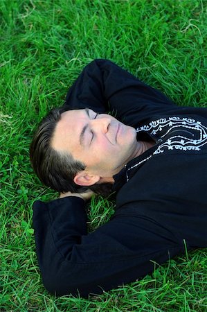 simsearch:400-04790065,k - Man lying on the grass in a zen position with eyes closed, resting. Photographie de stock - Aubaine LD & Abonnement, Code: 400-04464530