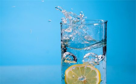simsearch:6113-06626095,k - lemon splash in transparent glass over blue background Stock Photo - Budget Royalty-Free & Subscription, Code: 400-04468421