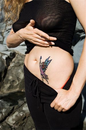 Caucasian mid-adult woman revealing tattoo of fairy on stomach. Stock Photo - Budget Royalty-Free & Subscription, Code: 400-04468836