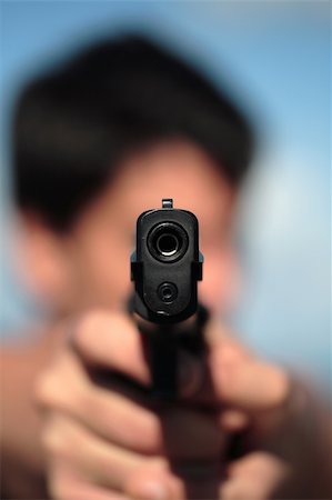 police officer pointing - A young, robust man, in his 20's with dark hair pointing 2 pistols to the camera. Stock Photo - Budget Royalty-Free & Subscription, Code: 400-04469799