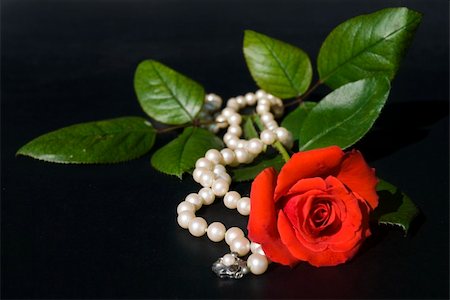 Necklace of mallorca pearls and roses on a black background in warm natural light. Narrow dof on roses. Foto de stock - Royalty-Free Super Valor e Assinatura, Número: 400-04469873