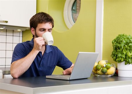 Using a laptop computer in the kitchen while enjoying a warm drink Stock Photo - Budget Royalty-Free & Subscription, Code: 400-04462114