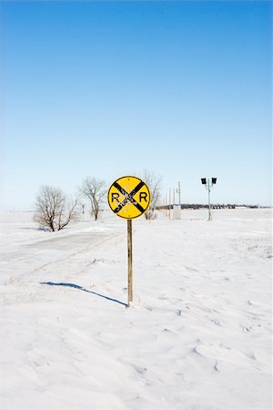 passagem de nível - Railroad crossing sign in snow covered rural landscape. Foto de stock - Royalty-Free Super Valor e Assinatura, Número: 400-04463305