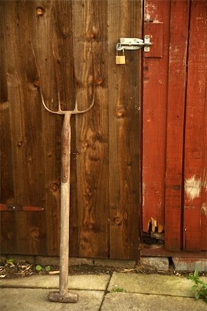 rastrellino - A pitchfork laying against an old wooden door. Fotografie stock - Microstock e Abbonamento, Codice: 400-04463711
