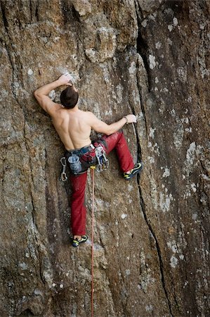 simsearch:400-04463866,k - A male climber against a large rock face climbing lead against a magnificant landscape. Stockbilder - Microstock & Abonnement, Bildnummer: 400-04463879