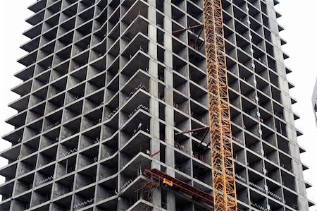 flyfishka (artist) - Large highrise under construction. One giant metal cranes against ever towering building exterior Stockbilder - Microstock & Abonnement, Bildnummer: 400-04477523