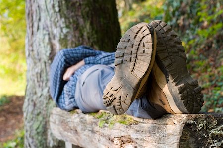 Hiker lying on a wooden bench. Focus on the boots in the foreground. Stockbilder - Microstock & Abonnement, Bildnummer: 400-04479401